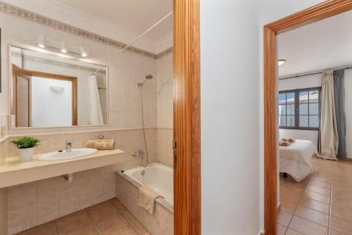 a bathroom with a sink and a tub and a mirror at Villa Timanfaya in Tías