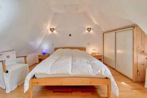 a bedroom with a large white bed and a chair at Maison cosy, 5 mins de St Lary in Sailhan