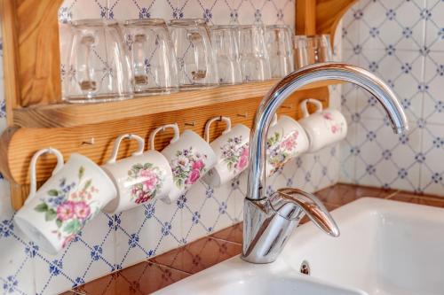 a kitchen sink with a faucet and cups on a wall at Casa Catalina in Sóller