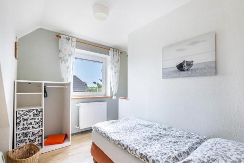 a bedroom with a bed and a window at Ferienhaus Dohle in Vollerwiek