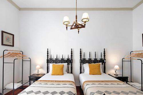 two beds in a room with a chandelier at Sé Heritage in Angra do Heroísmo