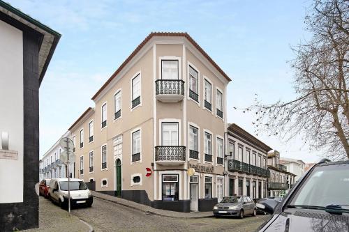 a tall building with cars parked in front of it at Sé Heritage in Angra do Heroísmo