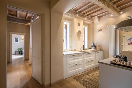 a kitchen with white cabinets and a hallway with a window at Radicondoli House in Radicondoli