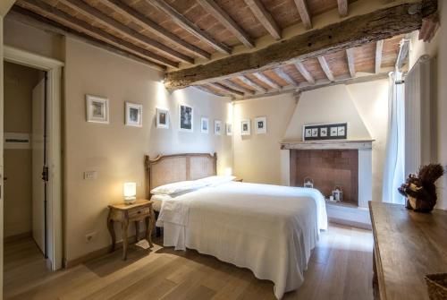 a bedroom with a white bed and a fireplace at Radicondoli House in Radicondoli