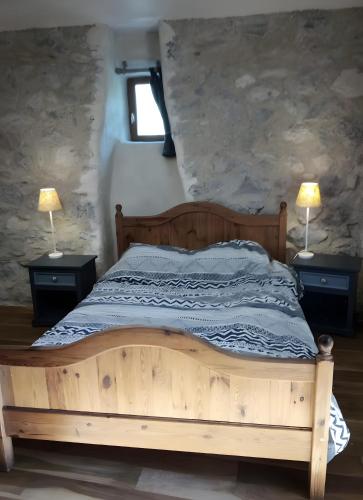 a bedroom with a wooden bed with two lamps on tables at Ferme Des Montagnes Bleues in Bellegarde-en-Diois