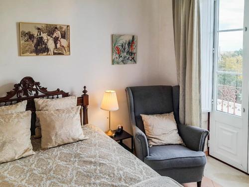 a bedroom with a bed and a chair and a window at Estoi Heritage in Estói