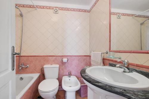 a bathroom with a toilet and a sink and a tub at Estoi Heritage in Estói