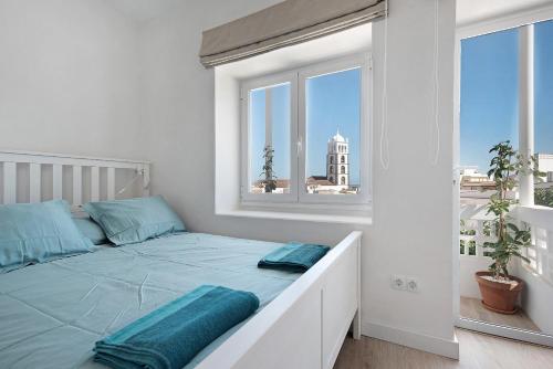 a white bedroom with a large bed with blue pillows at Casa Sol 21 A Garachico in Garachico