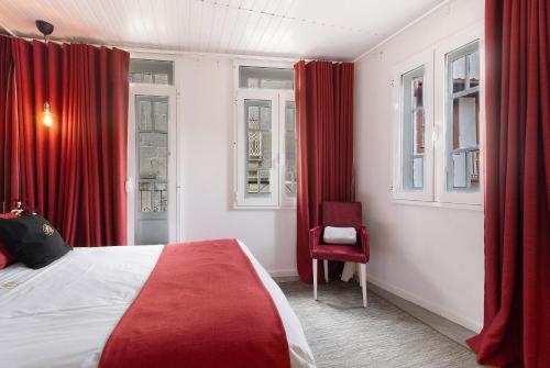 a bedroom with red curtains and a bed and a chair at Prestigegoldresidence 2 - Old Town in Guimarães