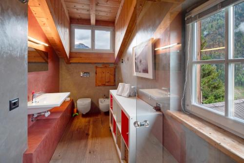 a bathroom with two sinks a toilet and a window at Dolomites Chalet Pian in Campitello di Fassa