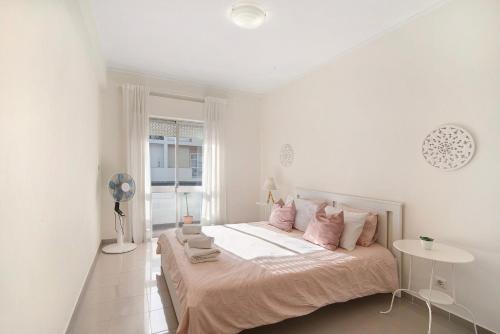 a white bedroom with a large bed with pink pillows at Matinhos House in Faro