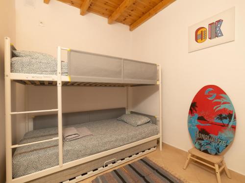 a bunk bed with a surfboard in a room at Casa 5 Flores in Odeceixe