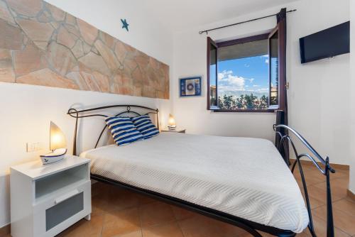 a bedroom with a bed and a window at Kai Mālie Villasimius in Villasimius