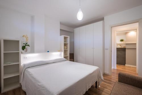 a white bedroom with a bed and a chair at Casa Cenate in Nardò