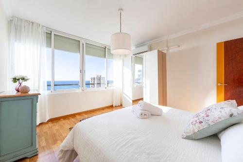 a bedroom with a white bed with a view of the ocean at Apartamento Loli in Aguadulce