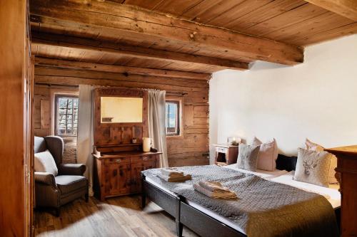 a bedroom with a bed and a chair in a room at Berghof Moosen in Hart im Zillertal