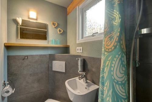 a bathroom with a sink and a toilet and a window at Tiny House in Lohfelden