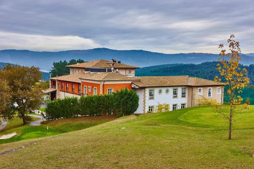 a large house on top of a grassy hill at Hotel Palacio Urgoiti in Mungia