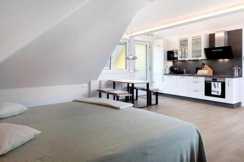 a white room with a bed and a kitchen at Ferienwohnung Hörnleberg in Gutach im Breisgau