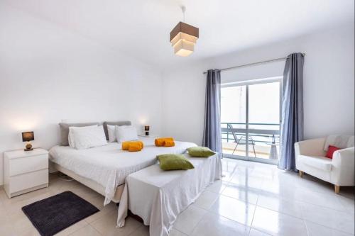 a white bedroom with a large bed and a chair at Casa Cláudia - Centro Histórico in Lagos