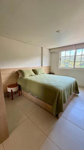 a bedroom with a green bed and a window at Granja Brasil , Studio Itaipava in Araras Petropolis