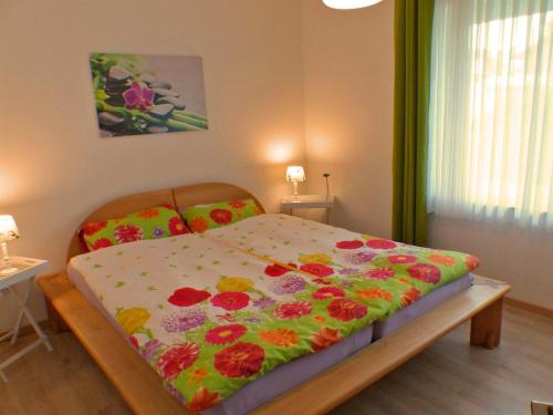 a bedroom with a bed with a flowered blanket on it at Ferienwohnung am Lerchenweg in Möhnesee