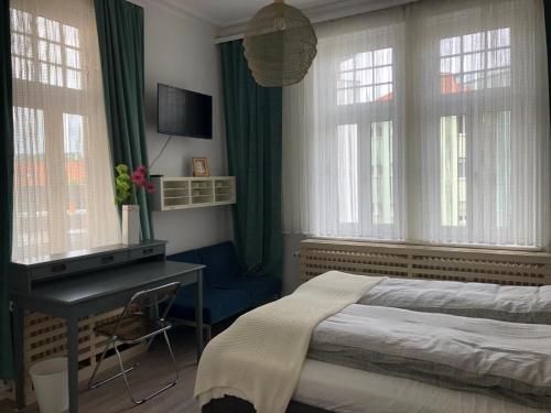 a bedroom with a bed and a desk and windows at Ferienzimmer Tübingen in Tübingen