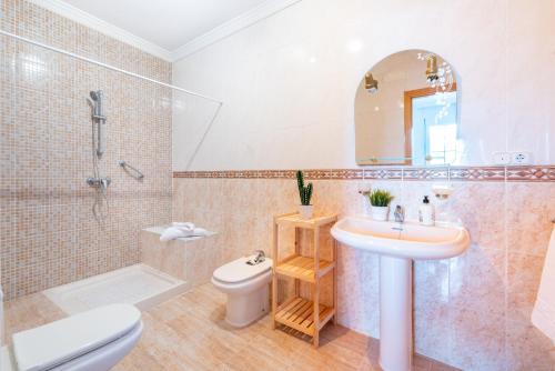 a bathroom with a sink and a toilet and a mirror at Villa Cañete in Benamocarra