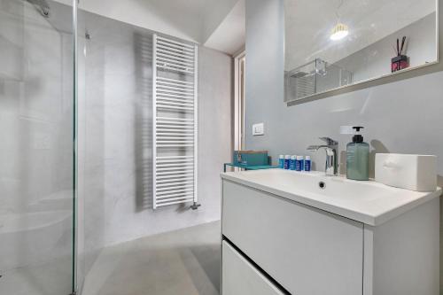 a white bathroom with a sink and a shower at La Gabbianella - Lake Como in Argegno