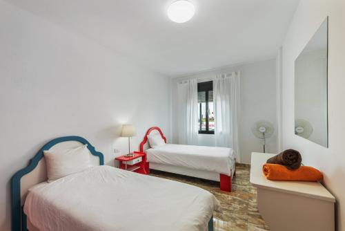 a white bedroom with two beds and a chair at Luján 1a Entre Hogueras Y Luces in Puntallana
