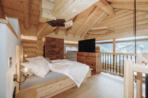 a bedroom in a log cabin with a bed and a television at Chalet Zwoasom in Grossarl
