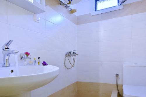 a white bathroom with a sink and a window at Erietas House in Ágios Matthaíos