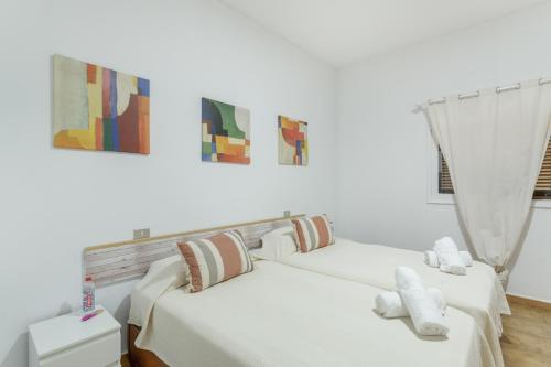 two beds in a white room with paintings on the wall at Casa Mar Azul Arinaga in Arinaga