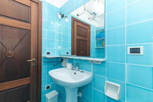 a blue tiled bathroom with a sink and a mirror at Le Giare 2 in La Maddalena