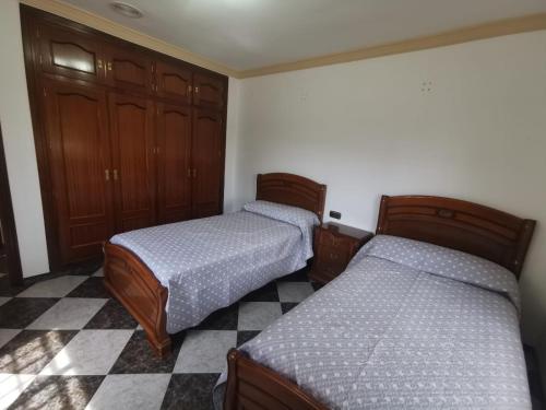 two beds in a bedroom with a checkered floor at Casa José Romero in Arriate