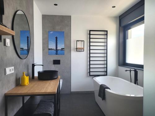 a bathroom with a tub and a sink and a mirror at Ferienhaus Schlossterrassen 8a in Pouch