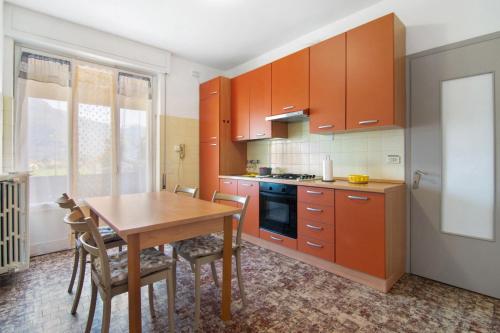 a kitchen with orange cabinets and a wooden table at Gravedona Holiday - Lake Como in Consiglio di Rumo
