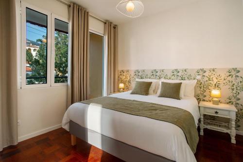 a bedroom with a large bed and a window at Casa do Loureiro in Funchal