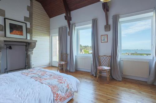 a bedroom with a bed and two large windows at Maison Chevoir pieds dans l'eau in Ploubazlanec