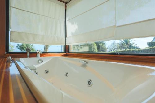 a large white bath tub in a room with a window at Maison Chevoir pieds dans l'eau in Ploubazlanec