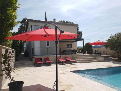 a red umbrella and chairs next to a swimming pool at Maison D'hôtes en Drôme Provençale in Vinsobres