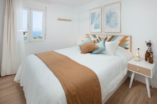 a bedroom with a bed with white sheets and pillows at Marineros Sureste A111 in Torre del Mar