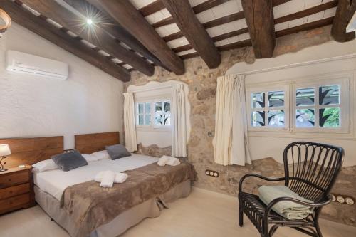 a bedroom with a bed and a chair and windows at Mas Juli in Pineda de Mar