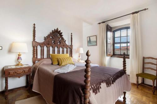 a bedroom with a bed with a wooden headboard and a window at Casa do Adro do Soajo in Soajo