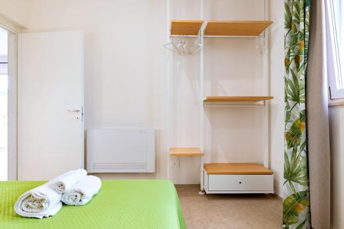 a bedroom with a green bed with towels on it at Helianthus in Cisternino