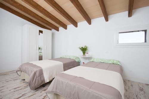 two beds in a room with white walls and wooden ceilings at Can Ferrer in Alcudia