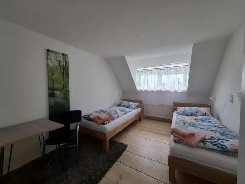 two beds in a room with a table and a desk at Ferienhaus Spes in Stockach