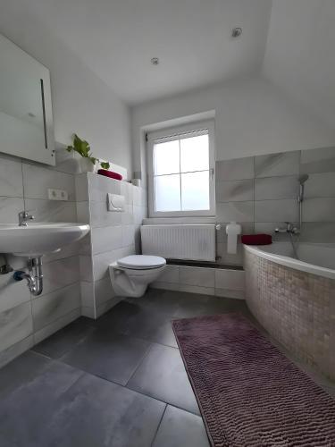 a bathroom with a sink and a toilet and a tub at Ferienhaus Spes in Stockach