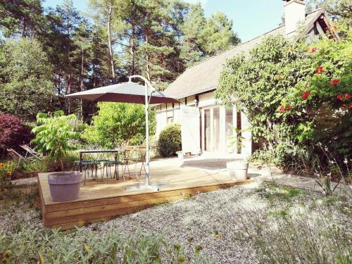 un ponte di legno con un tavolo e un ombrellone di La Maison D'amis a Souesmes