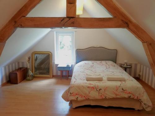 una camera da letto con un letto e uno specchio in una soffitta di La Maison D'amis a Souesmes